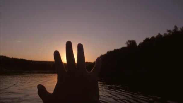 Palma mans toca sol, puesta de sol contra el fondo del río — Vídeo de stock