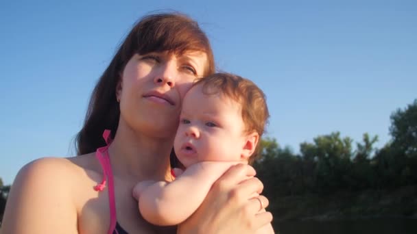Mãe beija bebê contra o céu azul . — Vídeo de Stock