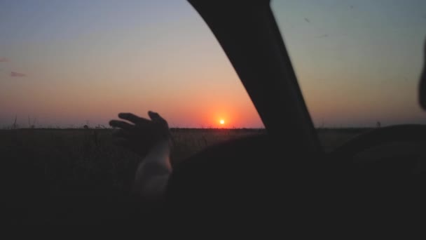 Stuurprogramma's hand rommelt met zon van autoruit tegen de prachtige zonsondergang — Stockvideo