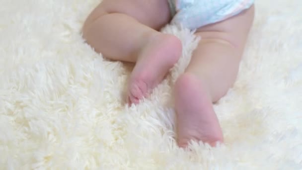 Bebé en pañal mueve sus piernas acostado . — Vídeos de Stock