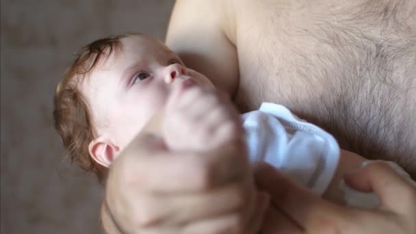 Bebé está acostado en los brazos de su padre y sonriendo . — Vídeo de stock