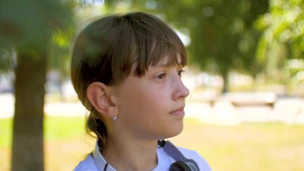 Το κορίτσι με τα ακουστικά που χαμογελά στο πάρκο καλοκαίρι. — Αρχείο Βίντεο