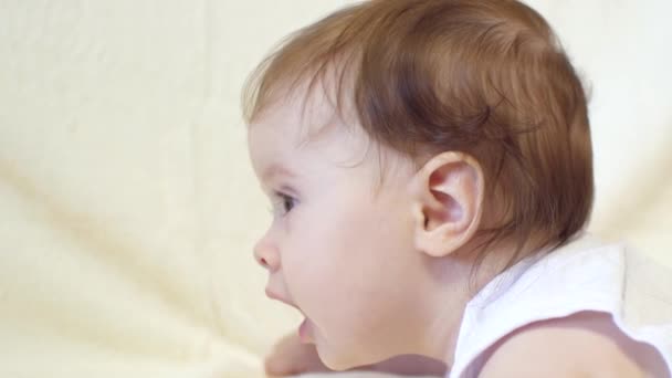 Un niño pequeño yace boca abajo, en la cama. . — Vídeos de Stock