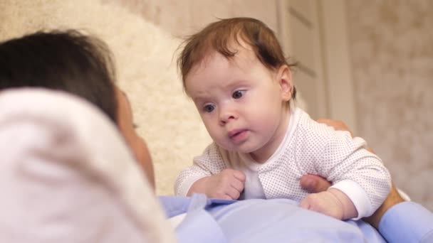 El bebé yace boca abajo sobre el pecho de su padre y el padre besa al bebé en la mejilla. Movimiento lento , — Vídeo de stock