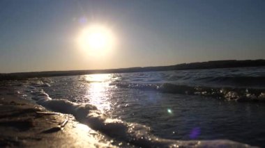 Dalgalar ve köpük gün batımına karşı. Ağır çekim.