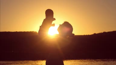 Bebek ve anne günbatımı kırmızı güneşe birlikte. Ağır çekim.