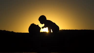 Anne bebek kırmızı günbatımı yukarıda atar. Ağır çekim.