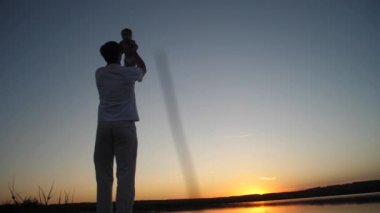 Baba bebek ile nehir banka ve altın günbatımı güneş dönüyor. Ağır çekim.