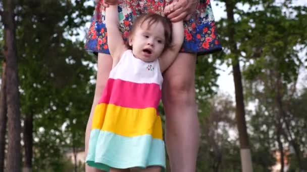 Mom teaches her little daughter to walk with her feet, holding her hands. — Stock Video