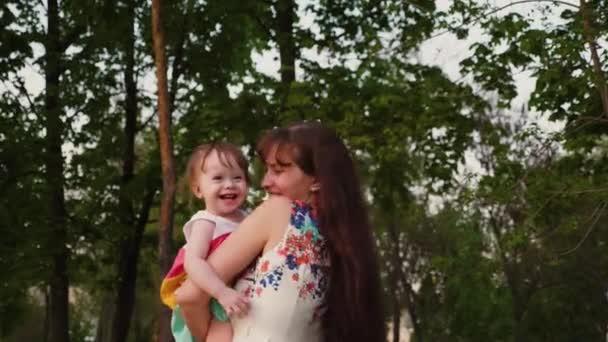 Giovane madre gioca nel parco con un piccolo bambino ridendo e scuotendo tra le braccia . — Video Stock