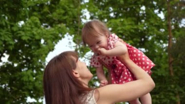 Bebek sevgi dolu anne boyuyla güler. Gülmek, birlikte parkta yürüyüş için oynayan bebek ve anne. Ağır çekim.