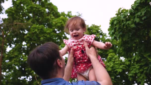 Baby lacht, als sein schöner junger Vater es durch die Luft pumpt. Zeitlupe. — Stockvideo