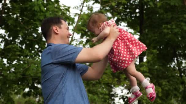 Happy dad turns his daughter on his hands walk with her in the green park. — Stock Video