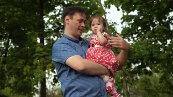 Rodič s dítětem mávl rukou a usmívá se v zeleném parku — Stock video