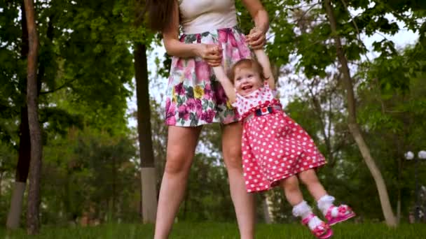 Mamá se balancea feliz bebé en sus brazos a través del aire . — Vídeos de Stock