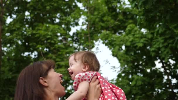 Joven mamá y el bebé riendo juntos mientras juegan al aire libre. Movimiento lento . — Vídeos de Stock