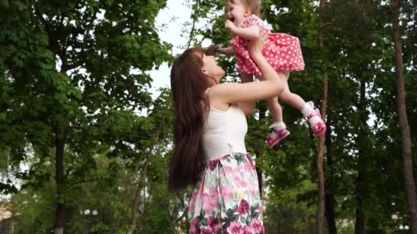 Das kleine Mädchen lacht und fliegt in den Armen ihrer Mutter durch die Luft. Mutterglück. Zeitlupe. — Stockvideo