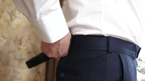 Man hand tighten trendy leather belt with shiny buckle on a men trousers. Closeup. — Stock Video