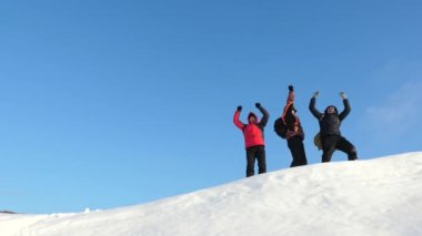 Alaskalı gezginler karlı bir tepenin tepesine gider ve kış gün batımına karşı zafer sevinirler. insanların takım çalışması. iş takım çalışması, zafer ve başarı. Turistler başarının zirvesinde buluştu.