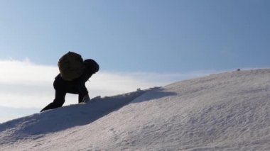Gezginler, yüksek rüzgarlarda kar altında el ele yükselerek zafere ulaşırlar. Turistler kışın birlikte çalışarak zorlukların üstesinden gelirler. Kışın üç dağcı dağda ipe tırmanıyor..