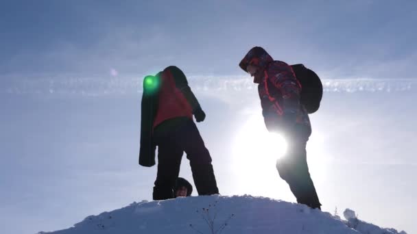 Alaskalı gezginler karlı bir tepenin tepesine gider ve kış gün batımına karşı zafer sevinirler. insanların takım çalışması. iş takım çalışması, zafer ve başarı. Turistler başarının zirvesinde buluştu. — Stok video