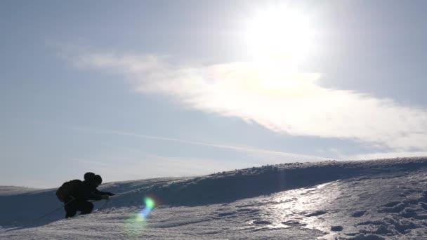 Les voyageurs grimpent à la corde à leur victoire à travers la neige en montée dans un vent fort. touristes en hiver travaillent ensemble comme équipe pour surmonter les difficultés. trois alpéistes en hiver grimpent à la corde sur la montagne . — Video