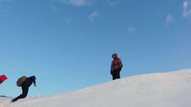 Οι ταξιδιώτες σκαρφαλώνουν στη νίκη μέσα από το χιόνι και συναντιούνται στην κορυφή του βουνού. τουρίστες το χειμώνα εργάζονται μαζί ως ομάδα ξεπερνώντας τις δυσκολίες. τρεις Alpinists το χειμώνα σχοινί αναρρίχησης στο βουνό. — Αρχείο Βίντεο