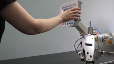 Bir işçi tablet bilgisayar kullanarak dikiş makinesini Cnc ile programlıyor. Operatör cnc makinesini ayarlar.