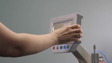 İşçi, tablet bilgisayar kullanarak bir dikiş makinesini Cnc ile programlıyor. Yakın plan. Operatör cnc makinesini ayarlar.