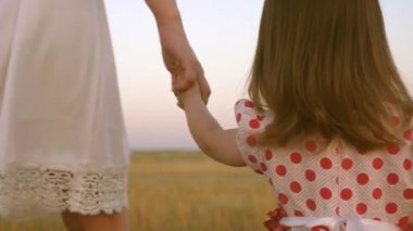 Mutlu çocukluk kavramı. Çocuk annelerin elini tutar, mutlu bir aile akşam şehir dışında yürür. Anne küçük kızıyla birlikte sahada yürüyor. Anne ve bebek parkta dinleniyor..