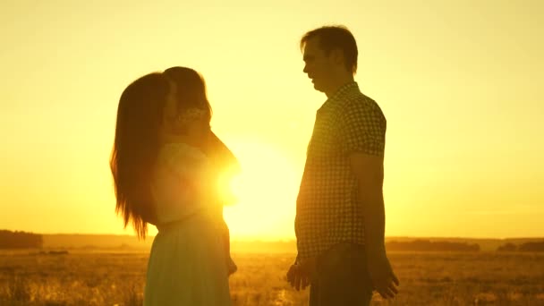 Silhouette of a happy family with baby in her arms at sunrise. Mom, dad and baby play in the sun. Concept. Parents and child laughs running from father to mother. Love guardians — Stock Video