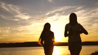 Günbatımında genç kız arkadaşlar tatil diskosu. Göl kenarında parti, dans eden çocuklar. Kumsalda dans eden mutlu kızlar. Güzel kızlar müzik dinleyerek eğleniyorlar. Kız kardeşler dans ediyor.