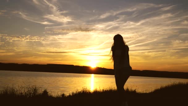 Chica feliz con el pelo largo está bailando al atardecer en la playa y riendo. Mujer libre y alegre. Movimiento lento — Vídeos de Stock