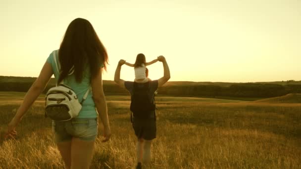 Teamwork. Familie mit Kindern ist in den Ebenen und Bergen unterwegs. Der Vater trägt eine kleine Tochter auf den Schultern, eine glückliche Familie ist im Park unterwegs. Vater, Mutter Tochter Touristen. — Stockvideo