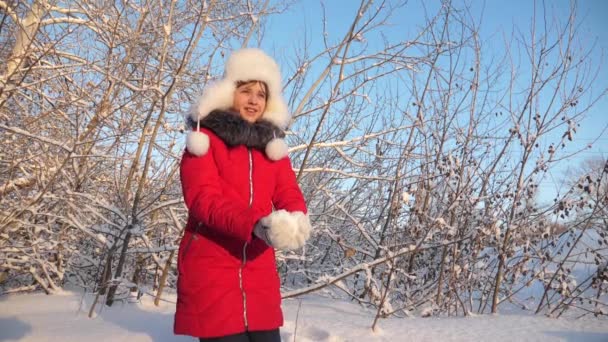 Niño juega en invierno en el parque para las vacaciones de Navidad. chica feliz vomita nieve con sus manos al atardecer en el bosque. Nieve cae y brilla al sol . — Vídeo de stock