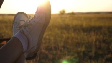 kadın arabayla seyahat eder. Genç kadın açık bir pencereden bacaklarını koyarak, bir araba seyahat seviyor. Araba camında bir kızın bacakları, güneşin parıltısı, kırsal yolda bir arabaya binme.