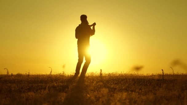 Vader en dochtertje dansen bij zonsondergang. Papa danst met een kind in haar armen in het veld in de zon. gelukkig kind speelt met zijn vader bij zonsondergang. Silhouet van man en kind. Gezinsconcept. — Stockvideo