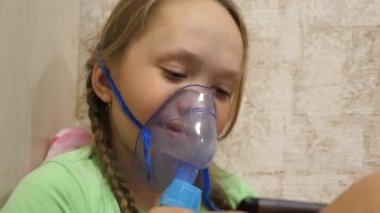 Tabletli çocuk hasta ve astım spreyinden nefes alıyor. Yakın plan. Hastanede yüzünde solunum maskesiyle tedavi edilen küçük bir kız. Yürümeye başlayan çocuk, solunum buharı soluyarak grip tedavisi görüyor..