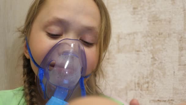 Hastanede yüzünde solunum maskesiyle tedavi edilen küçük bir kız. Tabletli çocuk hasta ve astım spreyinden nefes alıyor. Yakın plan. Yürümeye başlayan çocuk, solunum buharı soluyarak grip tedavisi görüyor.. — Stok video