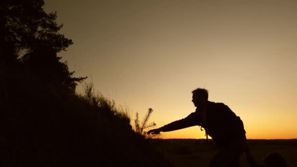 Viajero masculino y viajero femenino suben en la cima de la colina. trabajo en equipo de gente de negocios. los turistas descienden de la montaña al atardecer, uno tras otro. Familia feliz de vacaciones — Vídeos de Stock