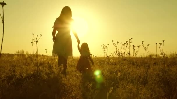 Mała córeczka i mama chodzą po boisku trzymając się za ręce. Dziecko trzyma mamę za rękę. Szczęśliwa rodzina wychodzi wieczorem z miasta. Matka i dziecko odpoczywają w parku. dziecko bawi się z matką w — Wideo stockowe