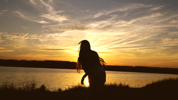 Fri och glad kvinna. Lycklig flicka med långt hår dansar vid solnedgången på stranden och skrattar. Långsamma rörelser — Stockvideo