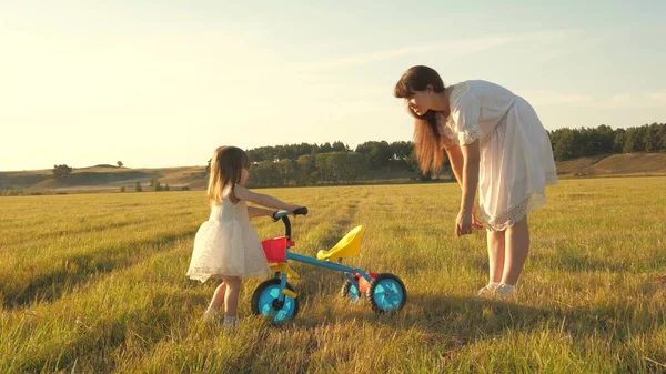 Mutter bringt Tochter Fahrradfahren bei. Mutter spielt mit ihrer kleinen Tochter. ein kleines Kind lernt Fahrrad fahren. Konzept einer glücklichen Kindheit. — Stockfoto