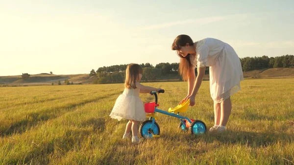 Annem kızına bisikletsürmeyi öğretir. Anne küçük kızıyla oynuyor. küçük bir çocuk bisiklete binmeyi öğrenir. mutlu çocukluk kavramı. — Stok fotoğraf