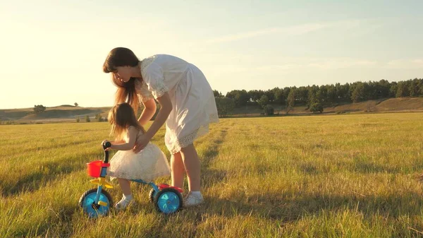 Mamma lär dotter att rida en cykel. Mamma leker med sin lilla dotter. ett litet barn lär sig att cykla. begreppet lycklig barndom. — Stockfoto