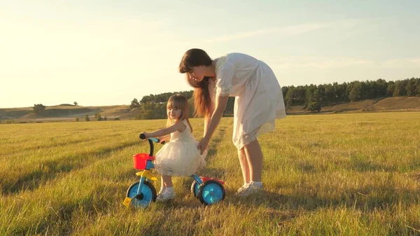 Moeder leert dochter om een fiets te rijden. Moeder speelt met haar kleine dochter. een klein kind leert fietsen. concept van Happy Childhood. — Stockfoto