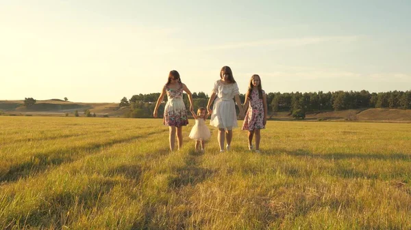 Parkta yürüyen kız kardeşleri olan bir anne ve küçük kız. Bir yaz tarlasında yürüyen çocuklu mutlu bir aile. Çocuklar ve anne çayırda oynuyorlar. Mutlu aile kavramı. — Stok fotoğraf