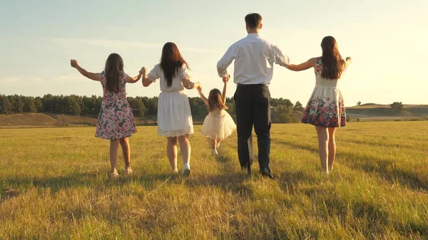 Madre, padre e hija pequeña con hermanas caminando en el campo bajo el sol. Feliz familia joven. Los niños, papá y mamá juegan en el prado bajo el sol. concepto de una familia feliz . — Foto de Stock