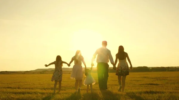 Mor, far och dotter med systrar som går i fält i solen. Lycklig ung familj. Barn, pappa och mamma leker på ängen i solskenet. begreppet lycklig familj. — Stockfoto