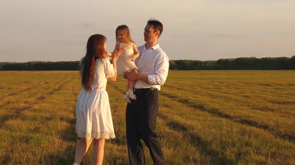 Glad pappa bär en liten dotter i sina armar och leker med sin mamma på planen. Föräldrar leker med barnet på en promenad. Familjebegreppet. Lagarbete. Begreppet lycklig barndom — Stockfoto